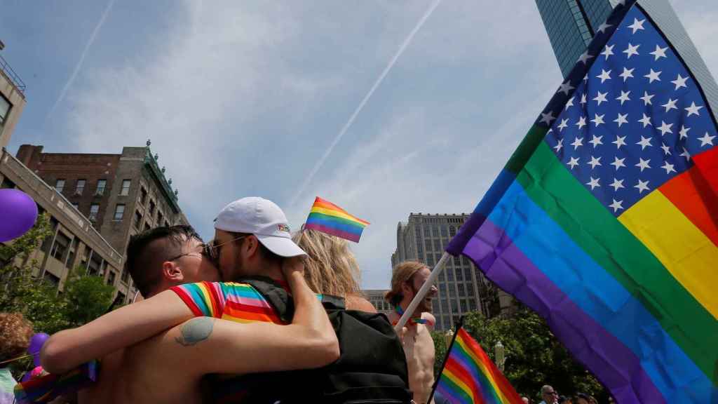 Dos personas se besan en EEUU portando una bandera arcoiris