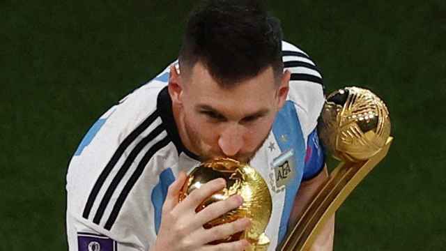Leo Messi, con el Balón de Oro del Mundial en la mano, besa la copa del mundo.