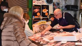 Varias personas hacen la compra en un puesto del mercado El Campillo de Valladolid