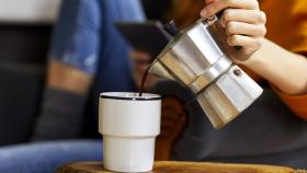 Una joven sirve una taza de café.