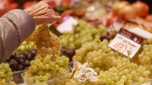 Una mujer coge un ramillete de uvas en el Mercado Central de Alicante.