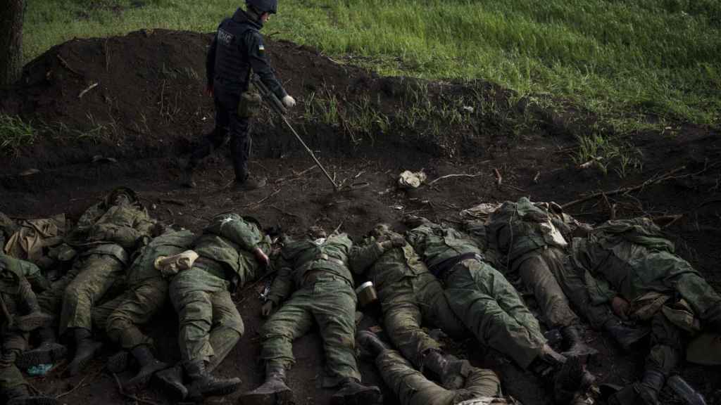 Un soldado ucraniano busca minas entre los cuerpos de 11 soldados rusos.