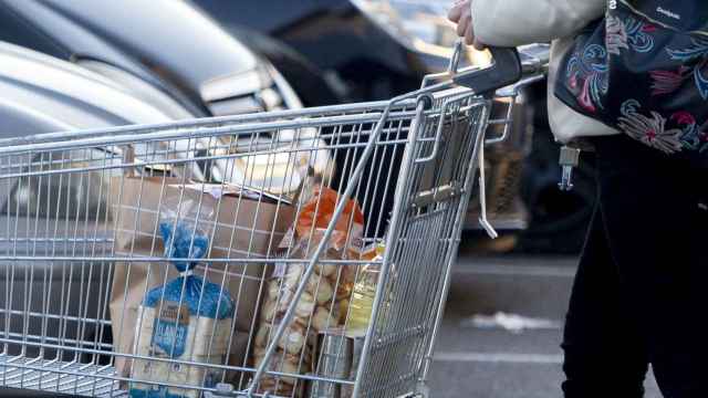 Una mujer sale de un supermercado con un carro de la compra
