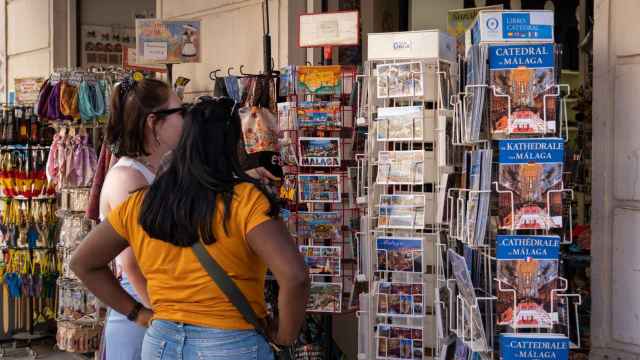 Dos turistas miran las postales en una tienda de 'souvenirs' del Centro Histórico de Málaga.