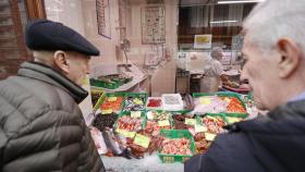 Dos personas observando los precios de una pescadería en Bilbao.