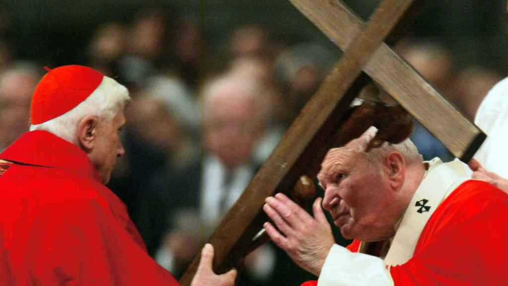 El papa Juan Pablo II besando el crucifijo de madera que sostiene el entonces cardenal Joseph Ratzinger, durante la Misa de la Pasión del Viernes Santo, en la Basílica de San Pedro, en el Vaticano, el 9 de abril de 2004.