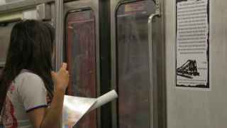 Una joven lee un poema pegado al vagón del metro