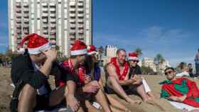 Unos turistas con gorros de Navidad disfrutan de las altas temperaturas en la playa de la Barceloneta, a 25 de diciembre de 2022, en Barcelona.