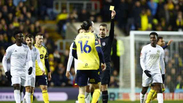 Árbitro enseñando una tarjeta amarilla en el Oxford-Arsenal.