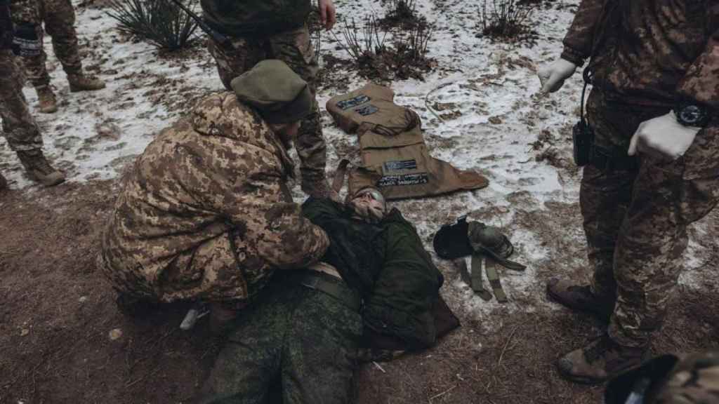 Soldados del Grupo Wagner junto a un soldado ucraniano ejecutado.