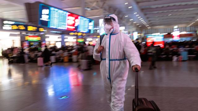 Un ciudadano chino camina en una estación con traje de protección a pesar de haberse rebajado las restricciones