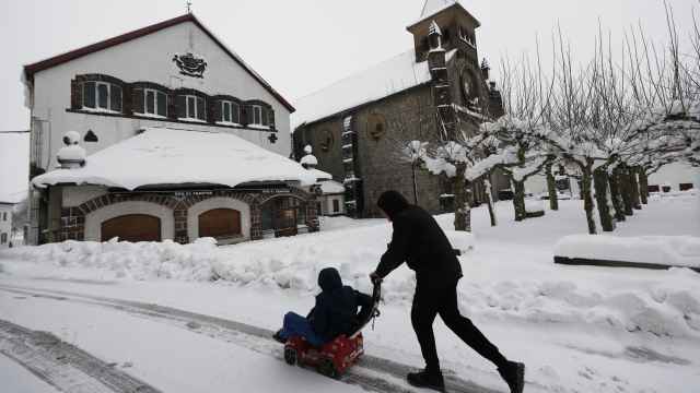Dos niños disfrutan con sus trineos entre la nieve acumulada en la localidad de Burguete.