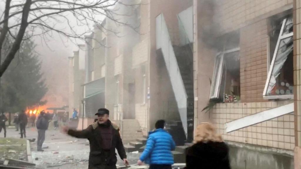 People running past a building moments after a helicopter crashed into it, in Brovary, kyiv, Ukraine, on January 18, 2023.