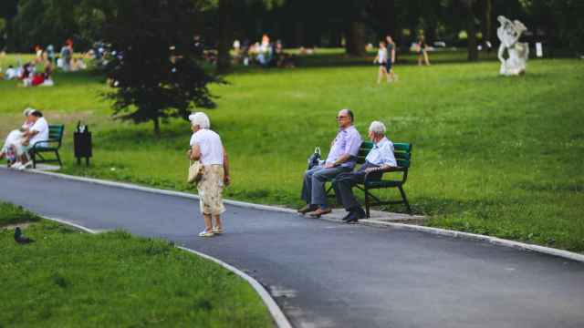 Varios jubilados sentados o paseando en un parque público.