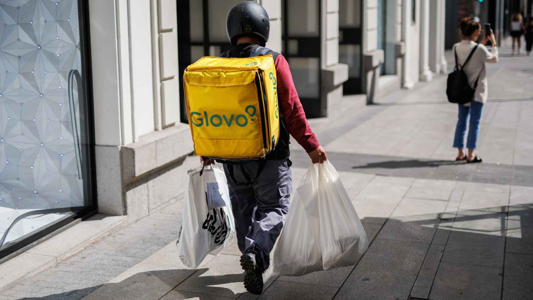 Un repartidor de Glovo con bolsas camina por una calle del centro de Madrid.
