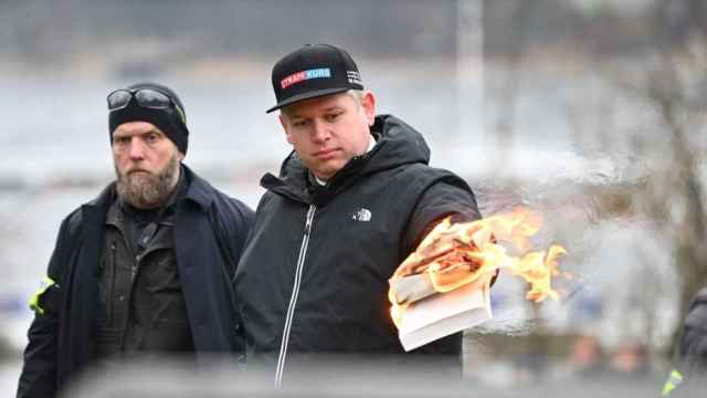 El ultraderechista sueco-danés Rasmus Paludan con un Corán en llamas en la mano.