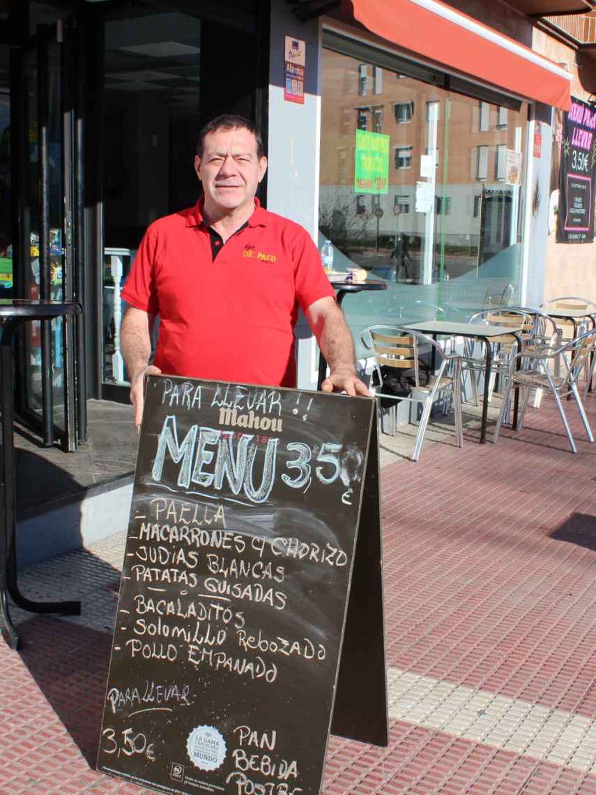 Paco, en la puerta de su bar, junto al cartel que anuncia el menú del día a 3,50 euros.