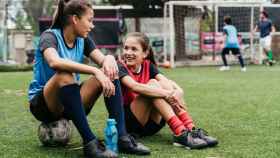 Dos chicas españolas hablando en un campo de fútbol.