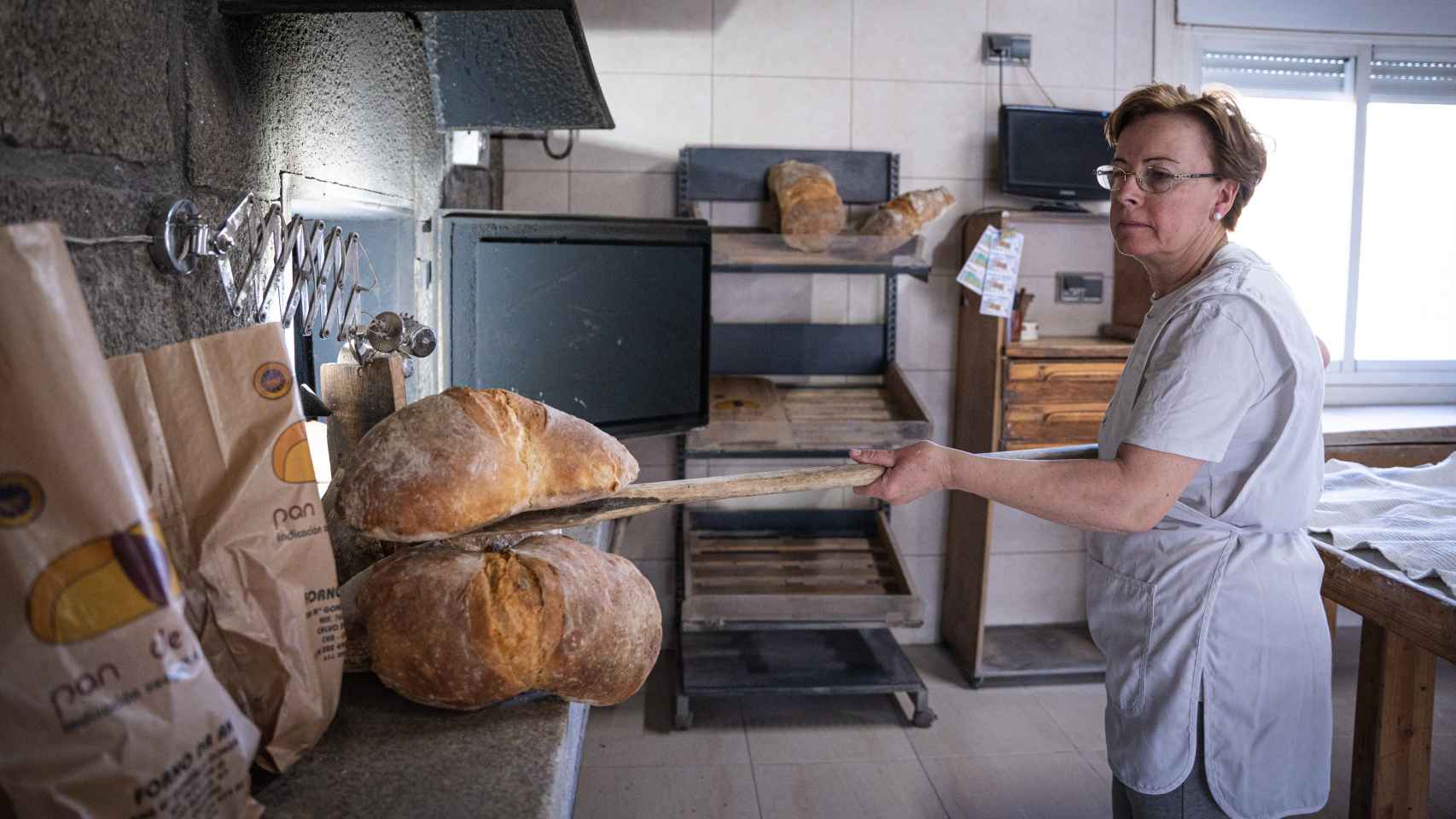 Ana González, panadera del Forno da Ana, sacando las 'poias' de pan de Cea recién horneadas.