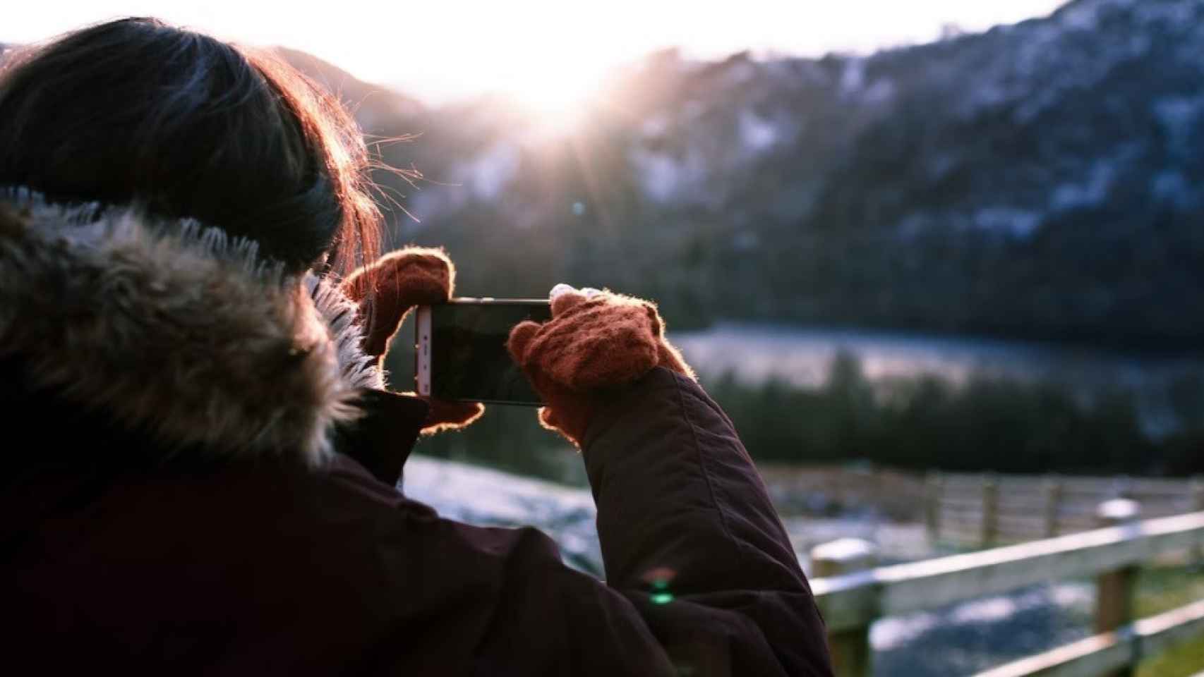 Una persona utilizando un smartphone para hacer una foto en el exterior.