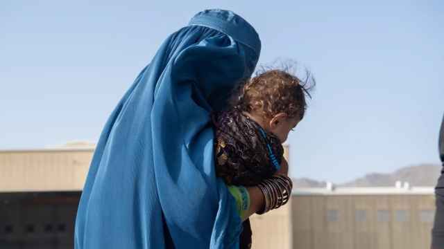 Una mujer afgana camina con su hija en brazos