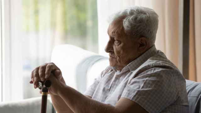 Un anciano con demencia mirando a través de la ventana.