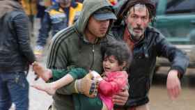 Ciudadanos sirios supervivientes del terremoto rescatan a una niña pequeña de entre los escombros.