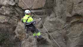 Un obrero trabaja en altura para colocar una red de protección en un talud del Valle, en Toledo.