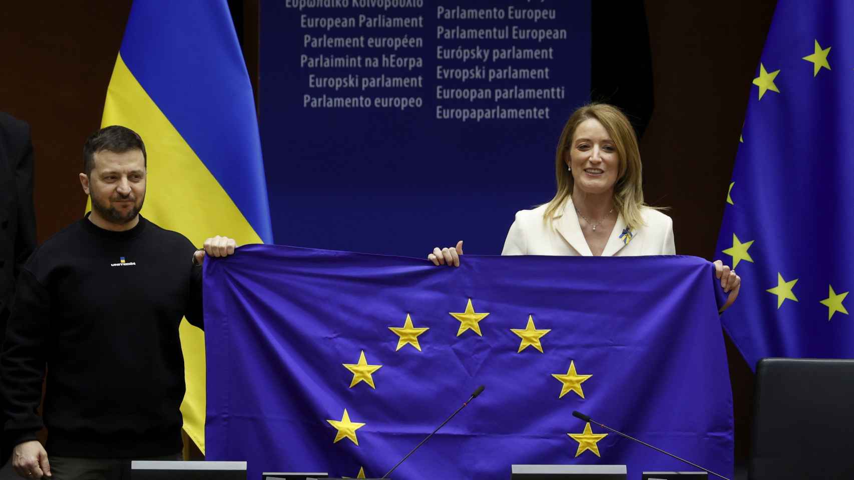 Volodímir Zelenski, presidente de Ucrania, sostiene una bandera de la UE junto a Roberta Metsola, presidenta del Parlamento Europeo.