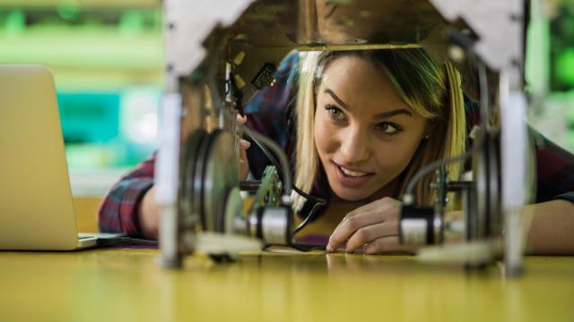 Foto de archivo de una mujer examinando un proyecto de robótica.