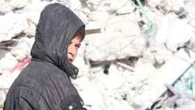 Un niño sirio frente a los escombros de un edificio