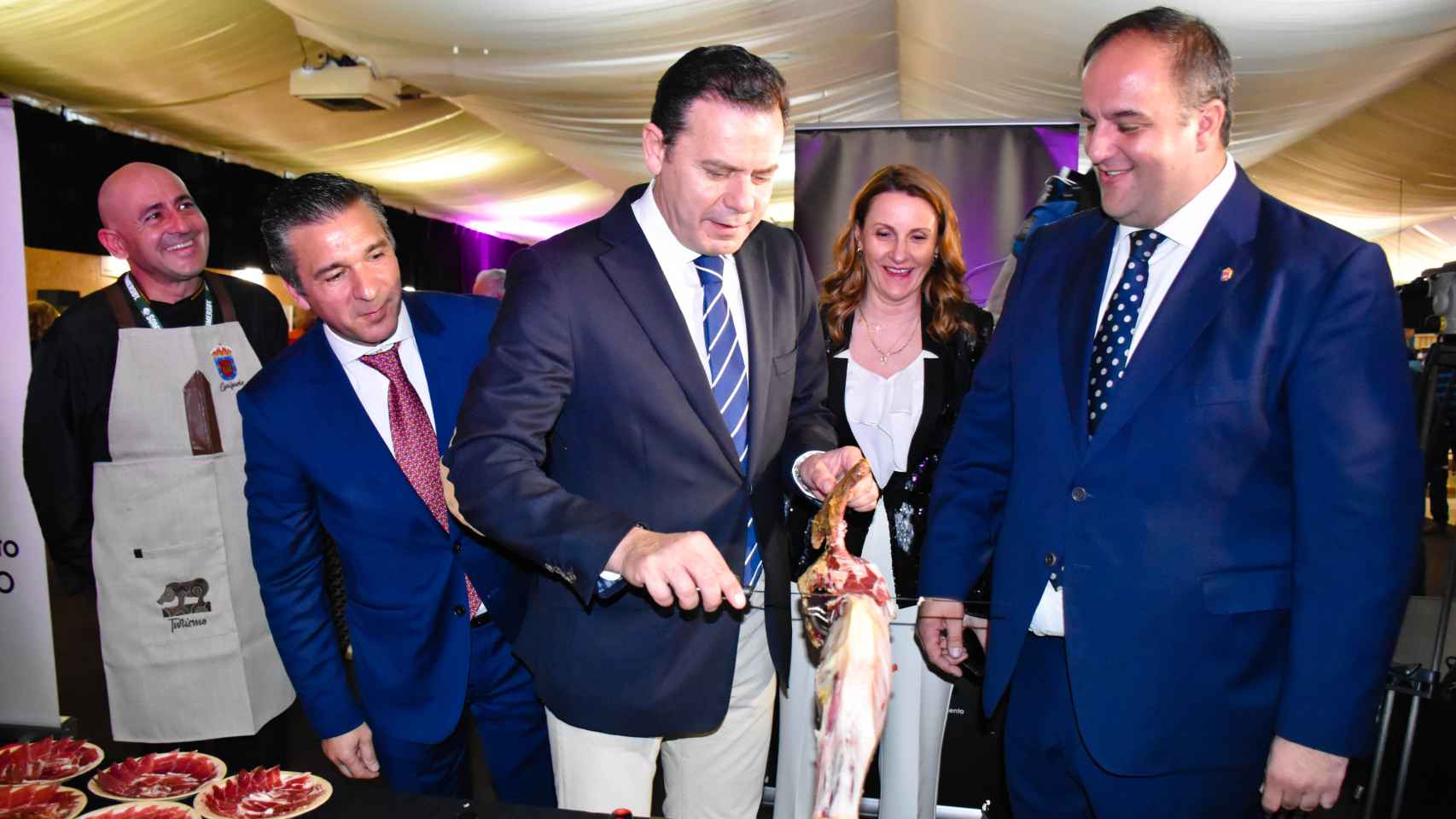 El presidente del PSD, Luís Montenegro, se atreve a cortar jamón en presencia de Rui Ventura y Roberto Martín, en el estand de Guijuelo