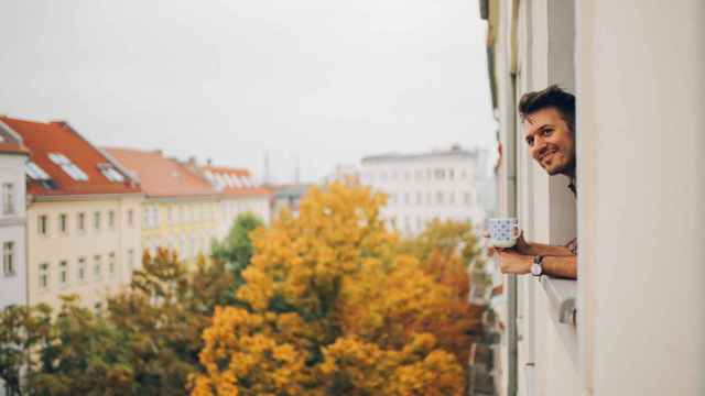 Un hombre mirando a través de la ventana de su apartamento en Prenzlauer Berg, Berlín