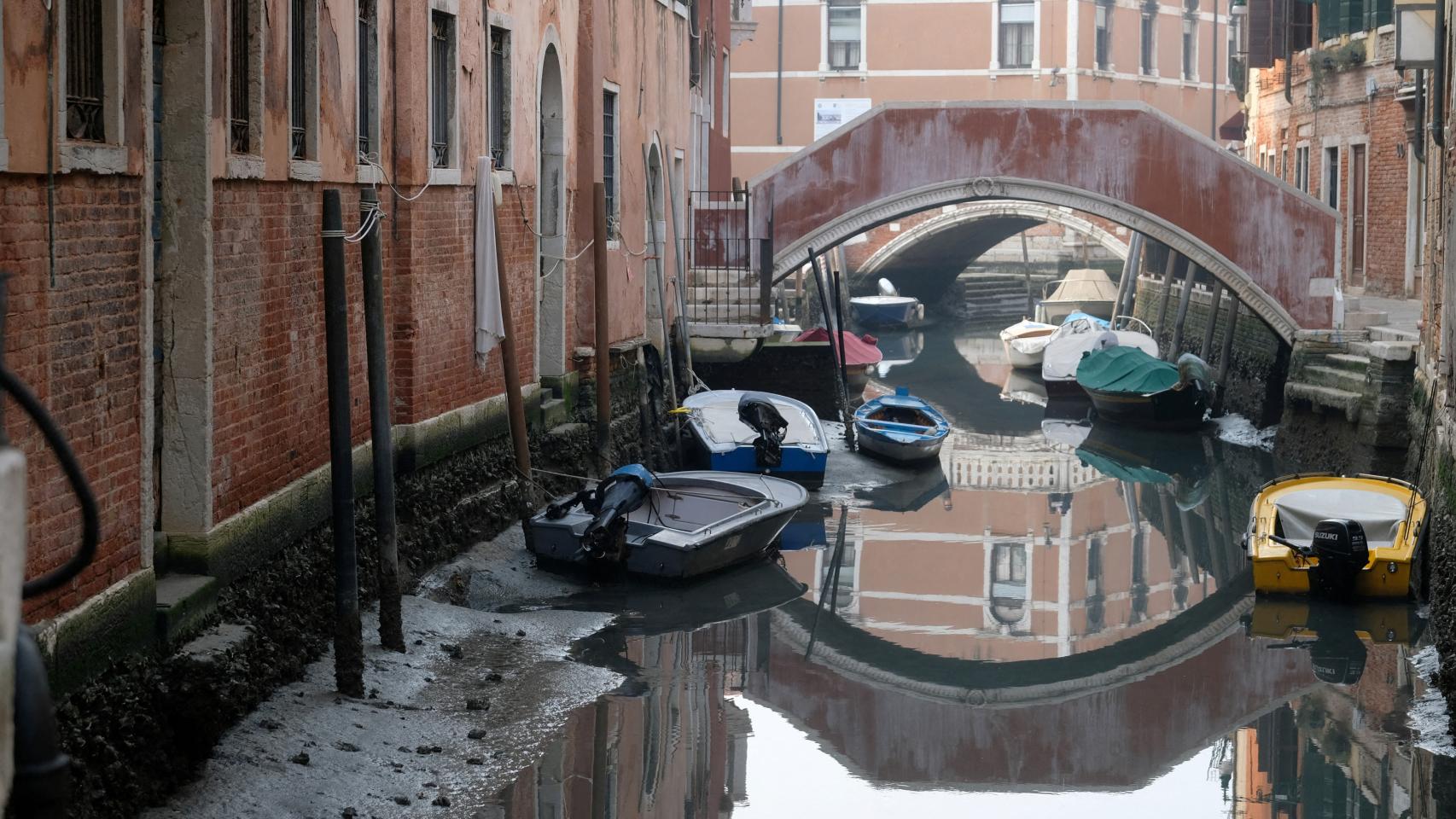 Boats in a canal during a strong low tide in the Venetian lagoon