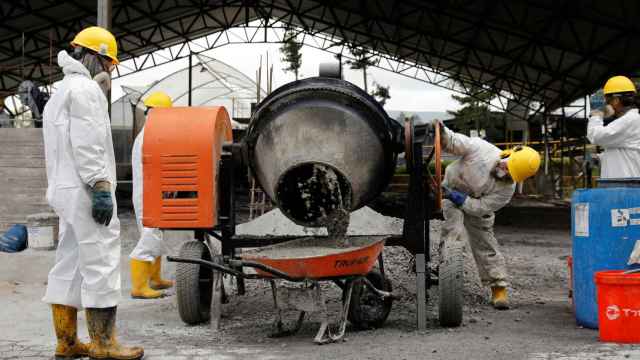 Trabajadores mezclan cocaína y pasta de coca incautadas con desechos industriales en una planta de tratamiento de desechos, en un lugar no revelado.