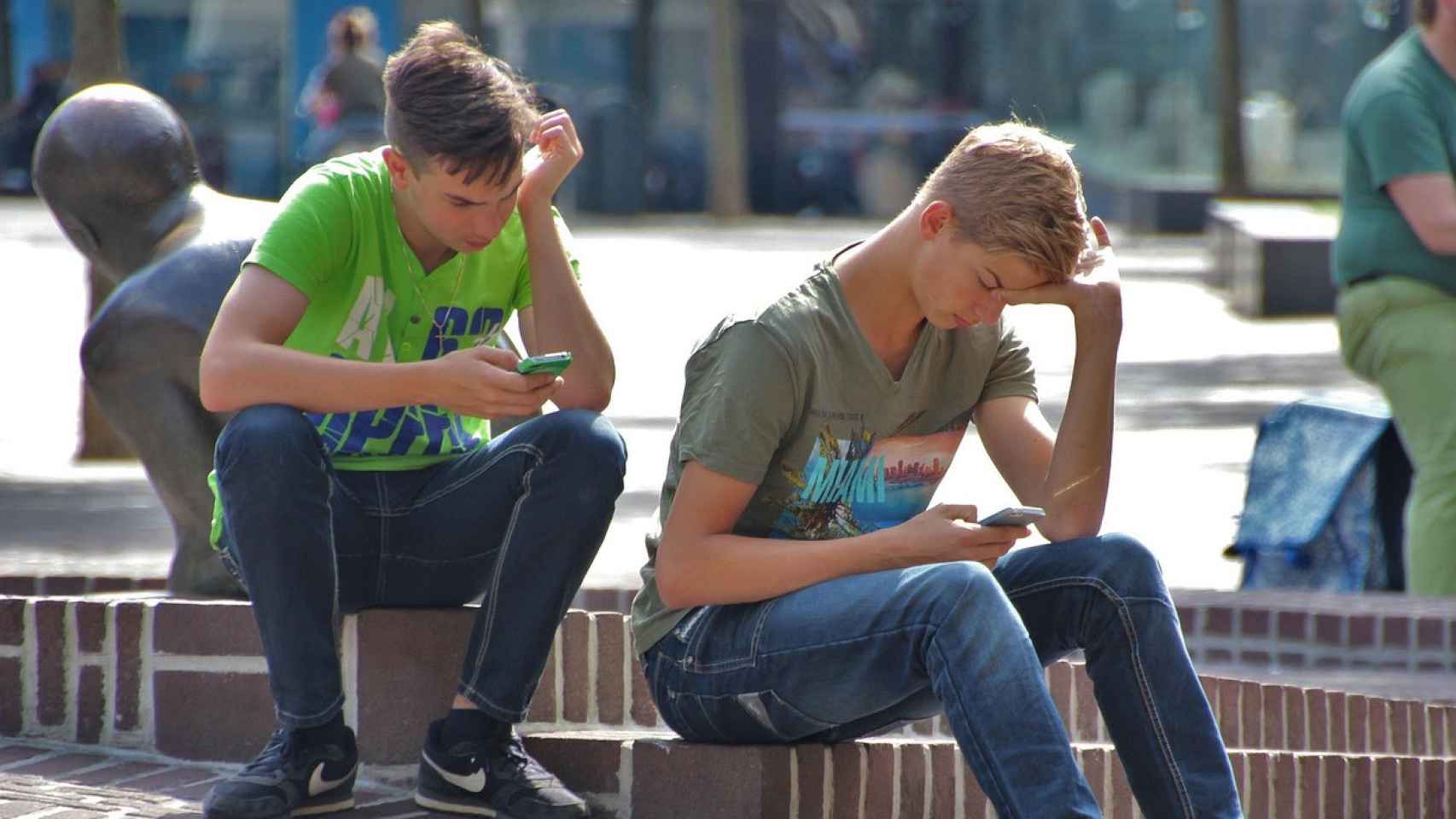 Dos adolescentes usan sus teléfonos móviles.