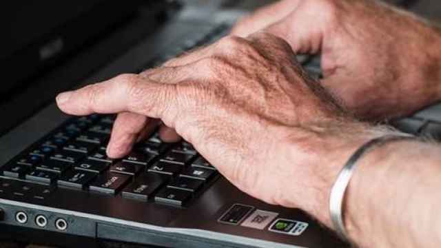 Una persona mayor escribiendo en el teclado de un ordenador.