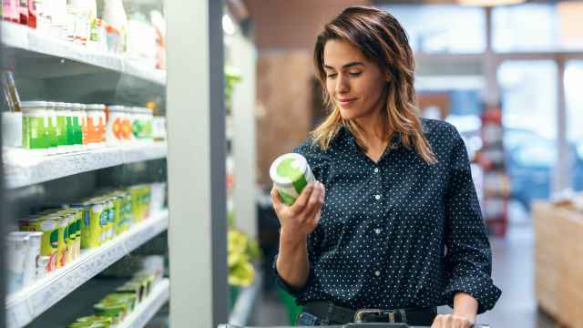 Una mujer mira la etiqueta de un producto en el supermercado.