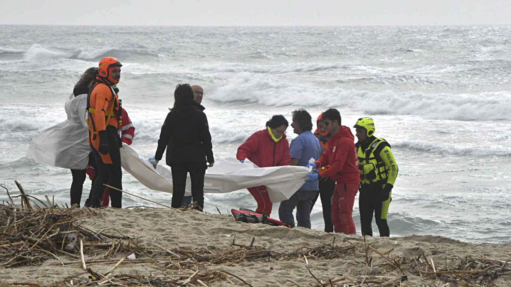 Rescatistas levantan los cadáveres que yacen en la playa.