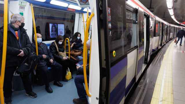 Varias personas con mascarilla dentro de un tren de Metro en la estación de Metro de Sol.