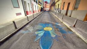 Una flor pintada en una alcantarilla de la calle Tablada.