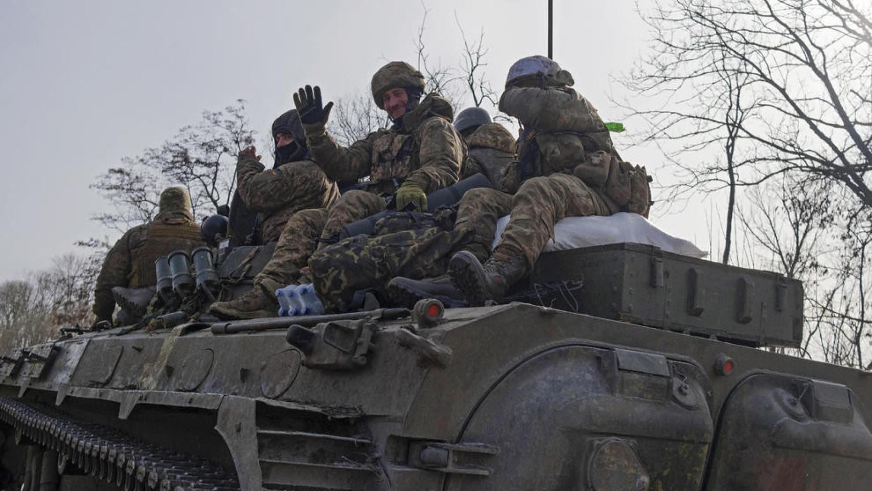 Ukrainian soldiers on top of an armored vehicle on a road in Bakhmut.