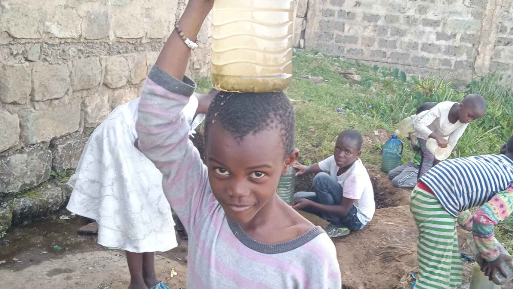 Niños recogiendo agua de charcos para lavarse.