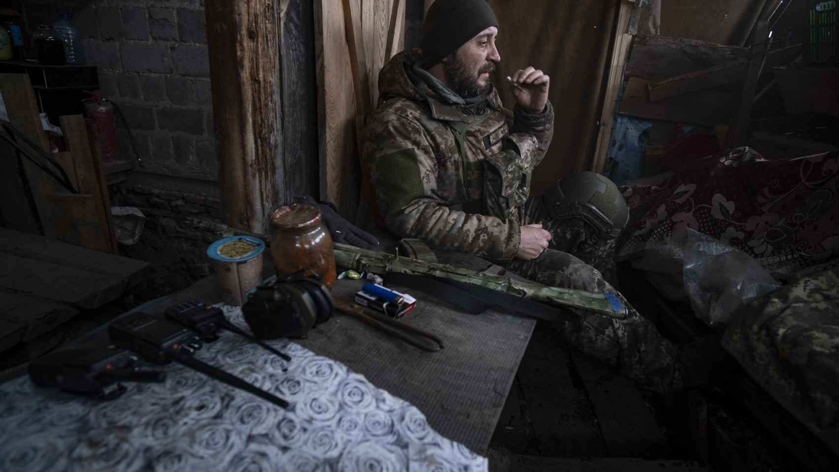 A Ukrainian soldier smokes a cigarette while watching radio communications in a trench, located at a point on the Vuhledar (Donetsk) combat front.