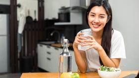 Imagen de archivo de una mujer bebiendo agua durante la comida.