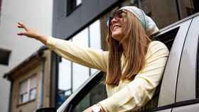 Una mujer luce un pañuelo en la cabeza asomada por la ventanilla de un coche.