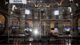 Panel de cotización de BBVA reflejado sobre el reloj del Palacio de la Bolsa de Madrid.