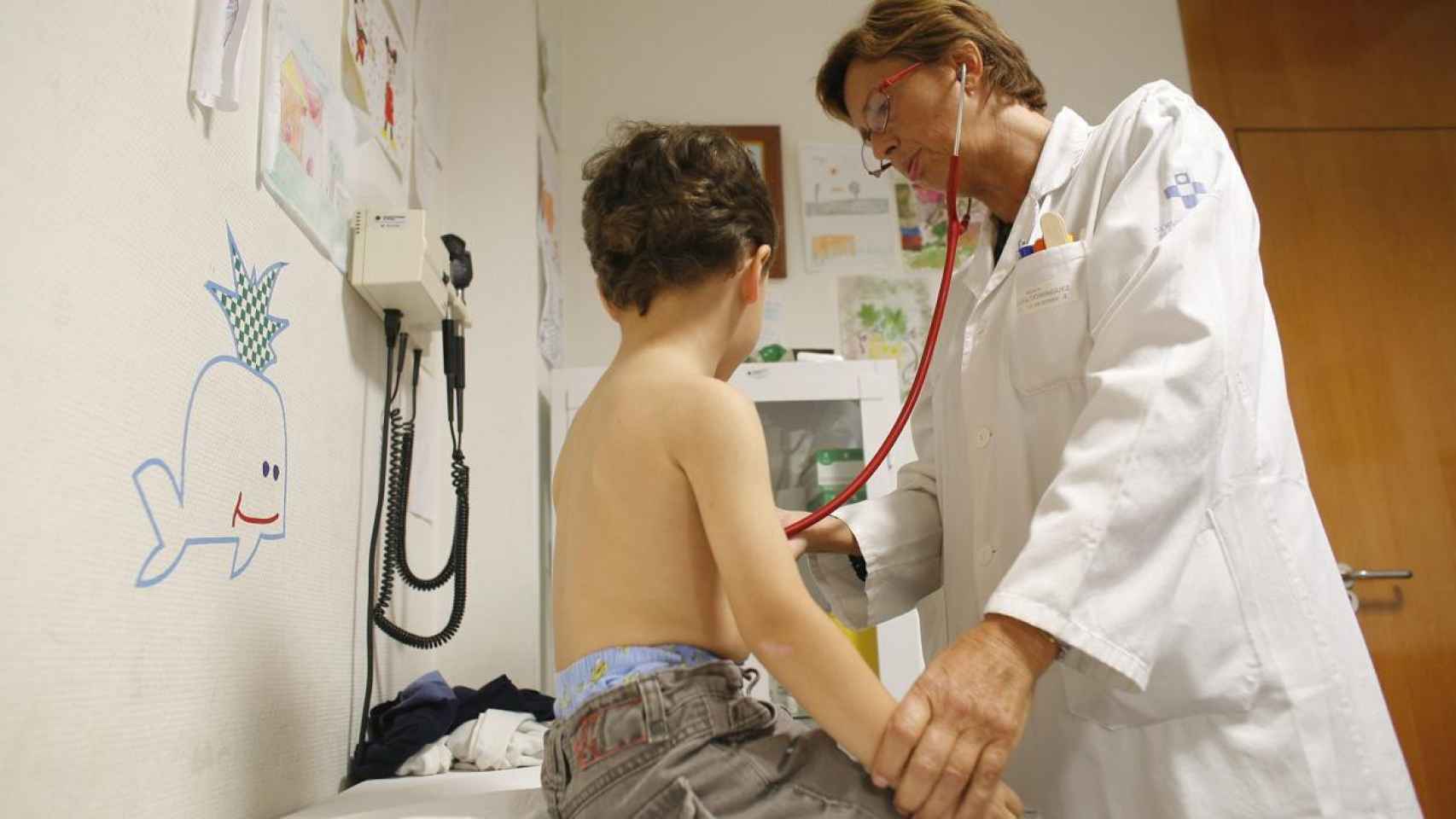Una pediatra pasa consulta a un niño.