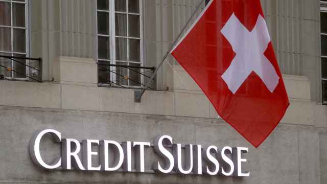 Una bandera de Suiza ondea sobre el logo de Credit Suisse en una de sus oficinas.