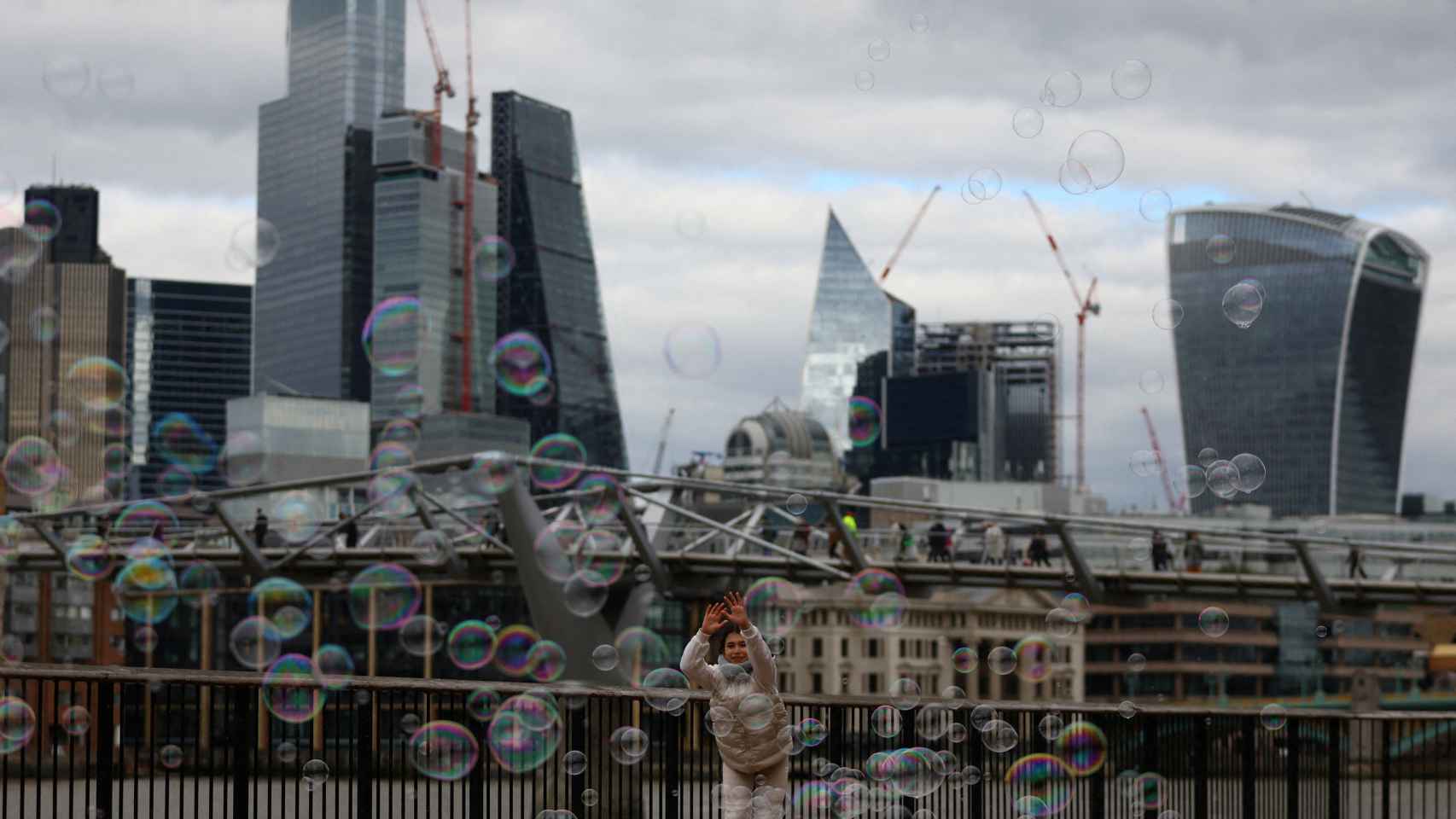 Una chica juega con pompas de jabón frente al distrito financiero de Londres.